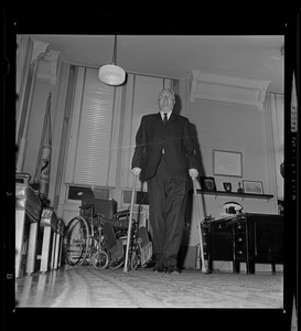 Mayor John F. Collins standing with crutches in his office