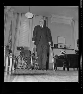 Mayor John F. Collins standing with crutches in his office