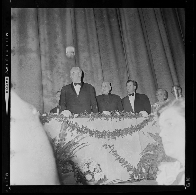 Boston Mayor John F. Collins, Richard Cardinal Cushing, and Sen. Edward M. Kennedy stand for national anthem at start of testimonial dinner honoring the Mayor