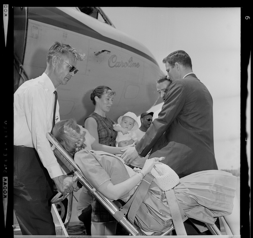 Marvella Hern Bayh in upright stretcher being carried onto the Kennedy family plane "Caroline"