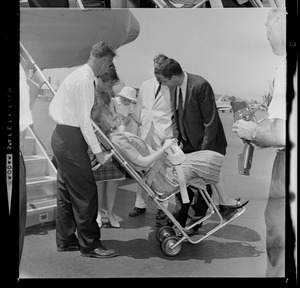 Marvella Hern Bayh in upright stretcher being carried onto the Kennedy family plane "Caroline"