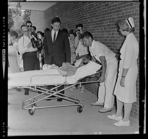 Marvella Hern Bayh being placed in an ambulance on a stretcher, with Sen. Birch Bayh and photographers watching