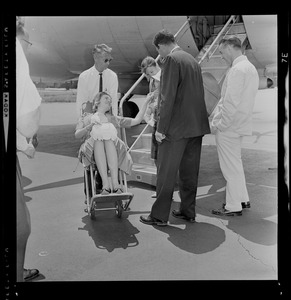 Marvella Hern Bayh in upright stretcher being carried onto the Kennedy family plane "Caroline"