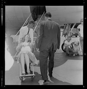 Marvella Hern Bayh in upright stretcher being carried onto the Kennedy family plane "Caroline"