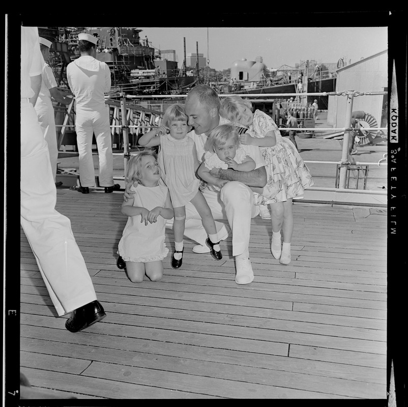 Sailor hugging four children after the USS Boston returns to Boston Naval Shipyard from training cruise