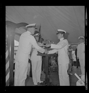Rear Admiral Joseph C. Wylie shaking hands and presenting diploma to Naval ROTC graduate at commissioning ceremony aboard Old Ironsides