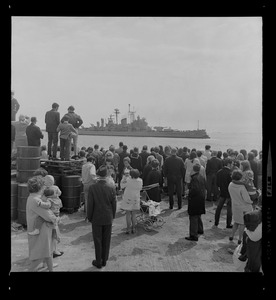 As the Boston-based USS Boston sails out of Boston Harbor for another tour of duty in Vietnam, tear-filled wives, friends and relatives of the crew wave their farewells from docks of the South Boston Naval Annex