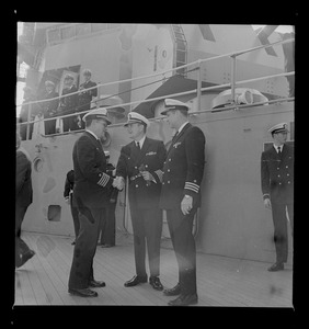 Navy captain meeting with two commanders on the deck of the USS Boston as it leaves the South Boston Naval Annex for tour of duty in Vietnam