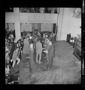 Young men give their draft cards to representatives of the National Mobilization Committee at an anti-draft rally at Arlington Street Church. "Boston Five" defendants Mitchell Goodman, Mike Ferber, William Sloane Coffin, and Dr. Benjamin Spock watch from front of stage