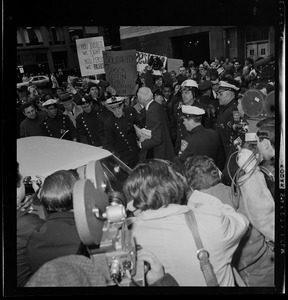 Dr. Benjamin Spock surrounded by protesters and police outside the Federal Building in Boston after his arraignment on charges of aiding draft resisters