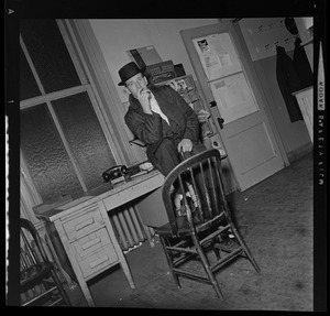 Unidentified man sitting on a desk, possibly in a newspaper office