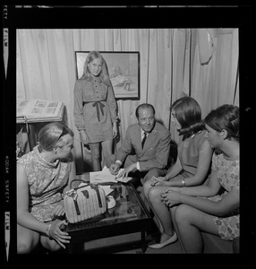 Unidentified man taking notes while talking to four unidentified young women