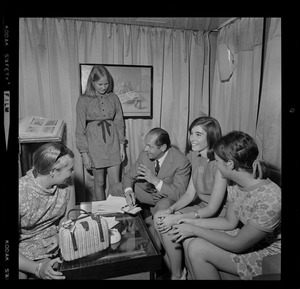 Unidentified man taking notes while talking to four unidentified young women