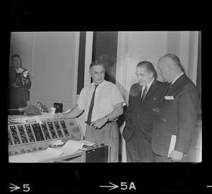 Two unidentified men and Paul A. Tamburello examining diagnostic machine