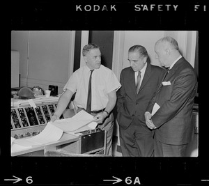 Two unidentified men and Paul A. Tamburello examining diagnostic machine