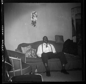 Man in suspenders is seated on a sofa