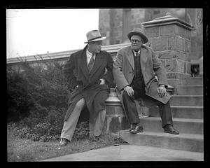 Two unidentified men seated by a set of steps