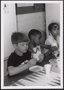 Three children sitting and eating