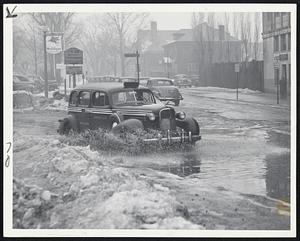 February Thaw--Rain, fog and rising temperatures melted much of the snow and ice in Greater Boston but make driving and walking conditions hazardous. Picture shows on automobile throwing spray as it passes through puddle at Essex and Mountfort streets.