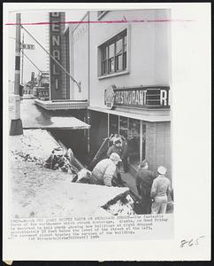 Quake Shifts Earth on Anchorage Street -- The fantastic force of the earthquake which struck Anchorage, Alaska, on Good Friday is depicted in this photo showing how buildings at right dropped approximately 10 feet below the level of the street at the left. The pavement almost touches the marquee of the building.