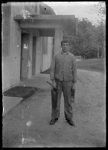Young man with hammer. In front of house w/ roof over entry