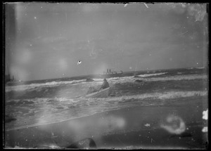 Beach. 2 men rowing dory just offshore