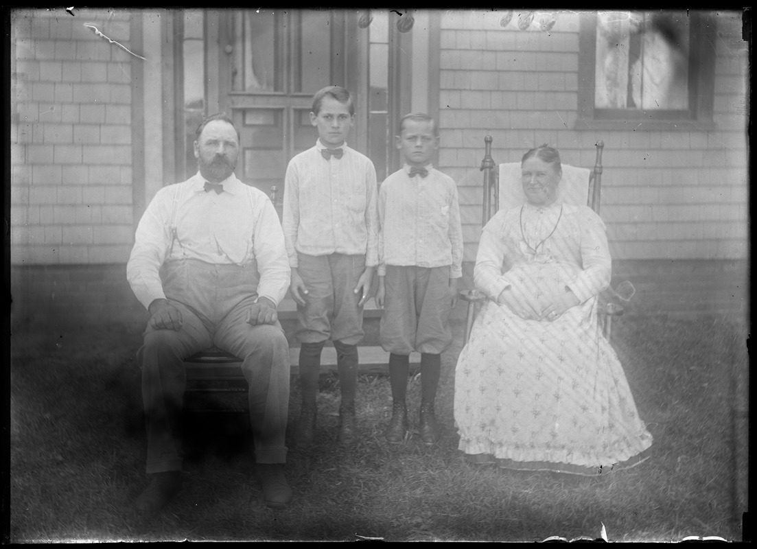 Stocky man, plump woman, early teenaged boys (2) on lawn in front of house
