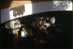 People eating at a restaurant, a sign of a cow in foreground