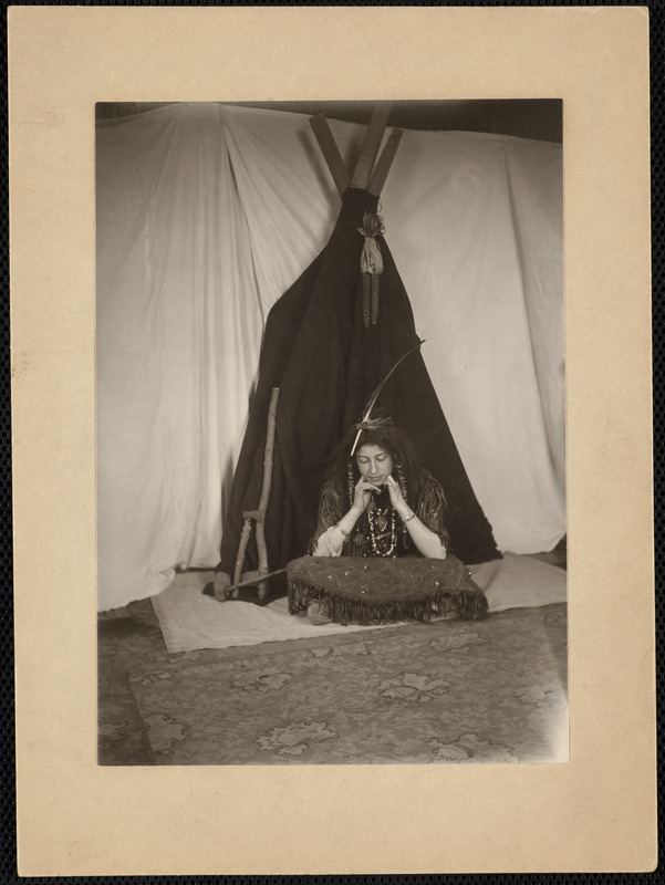 Seated woman dressed as an Indian in front of a teepee