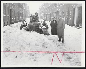 Opening Up A Street - Mayor Hynes and Public Works Commissioner Hyland watch as Thomas Schena of East Weymouth pits a powerful bulldozer against the snow piled on Melrose street in the South End. Police ordered five cars towed away before the narrow street could be plowed yesterday.