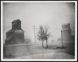 First Dust Storms Come to the Southwest. Guymon, Okla. -- Grain elevators assumed this ghostly appearance during one of the dust storms that passed over here late in January, the first in almost a year. Others were predicted throughout the winter and summer unless heavy rains or snow packed the already pulverized soil the plains states.