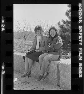Two women sitting on stone wall