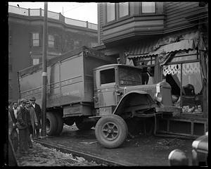 People gather near an A & J Motor Lines truck which has hit a storefront