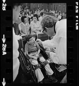 Crippled boy receives communion at orphanage mass, Brighton