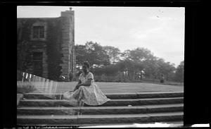 A woman sits on steps wearing a dress