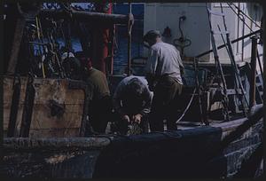 Three people working on a boat