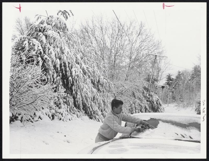 Motorists stops to clean his snow-covered windshield on Huckleberry Hill, Lincoln. The central and western parts of the state suffered a greater snow fall than the Boston region.