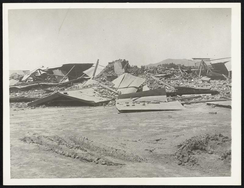 "City of Death..." Here is the ruined airmen's institute, at Quetta, India, where 26,000 persons died at the recent earthquake. These, the first pictures to leave the zone, were made as a double fence of barbed wire, patrolled by military and civil police, was set up about the wreckage.