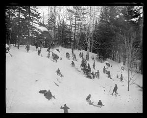 A group of people on a snowy hill mostly in snowshoes