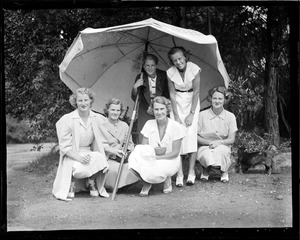 Women pose under big umbrella