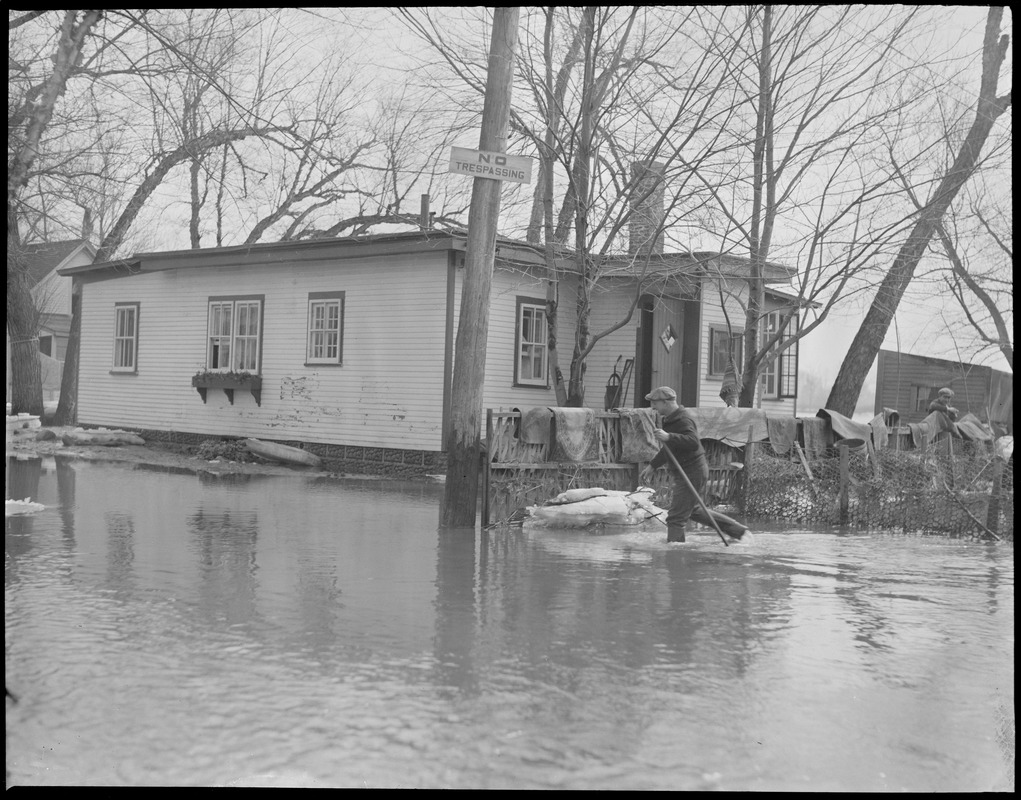 Man wades past cottage, New England flood