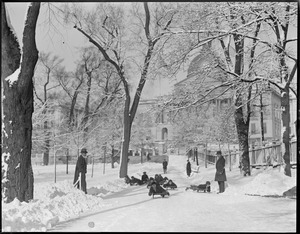 Kids sled on walkway on Boston Common, near State House