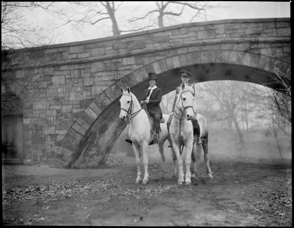 Man and woman on horseback under bridge at Muddy River