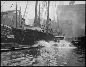 T-wharf flooded by storm. Autos splash by ship M.M. Hamilton.