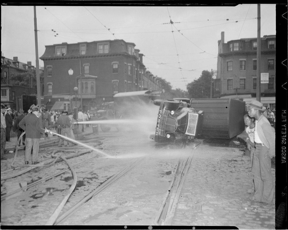 Firemen hosing down overturned truck