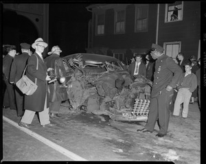 Firemen, police and press around wrecked auto