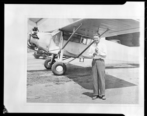 Douglas P. Corrigan, 31, of Los Angeles, standing beside his 1929 model plane in which he recently made a non-stop transcontinental flight from Long Beach. His expenses for the trip were $110.05 - the five cents for a chocolate bar.