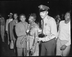 Injured Negro woman assisted by Negro police officer