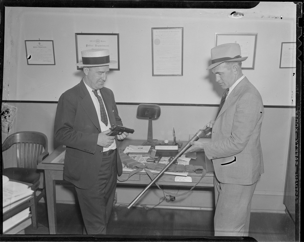 Special officers Vernon White (left) and Thomas McDonaough inspect guns seized in Charlestown during investigation into auto larceny