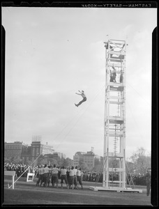 Fire man jumping from tower into safety net during fire dept. display on Boston Common